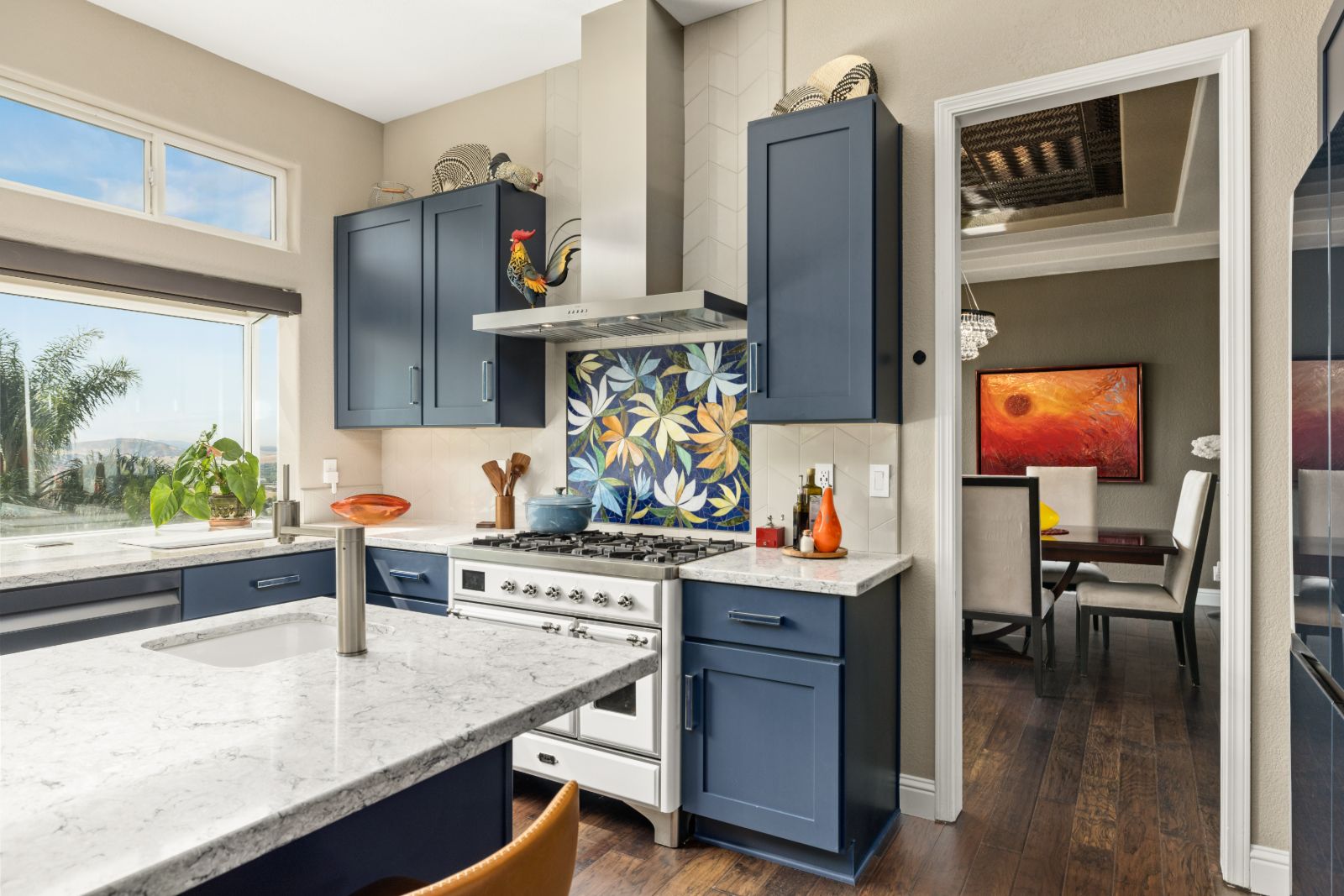 Two-island blue kitchen with quartz tops, white range and hardwood floors