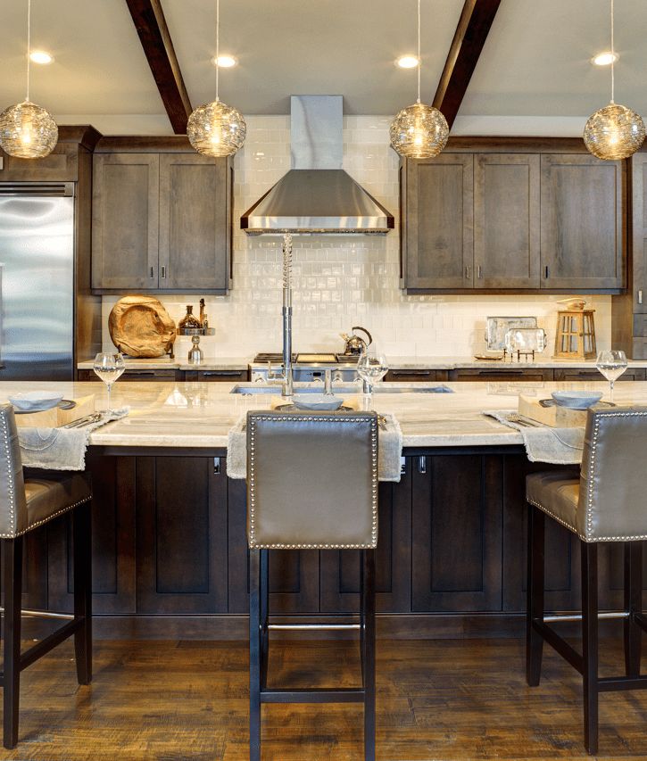 Dark stained kitchen with exposed beams, glass pendants and a stone-top seating island