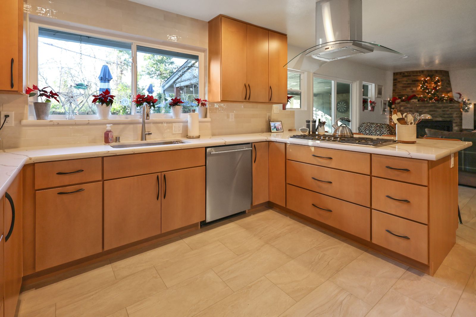L-shaped maple kitchen with quartz counters, glass hood and gas cooktop
