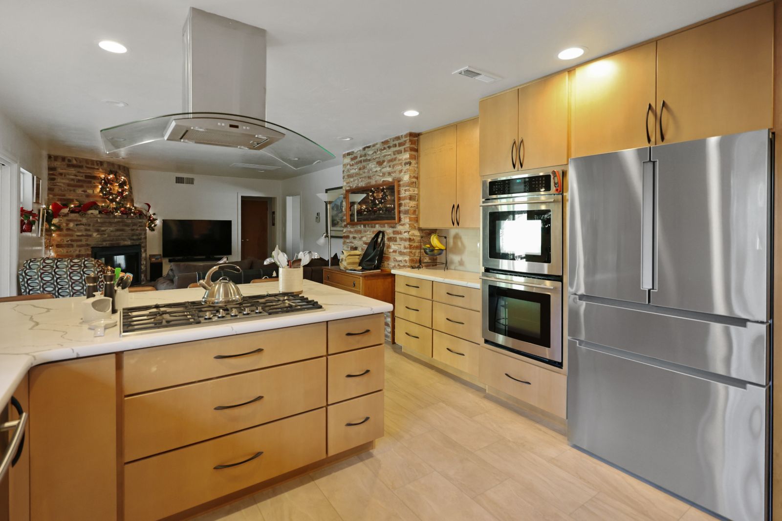 Open maple kitchen with quartz cooktop island looking into the family room
