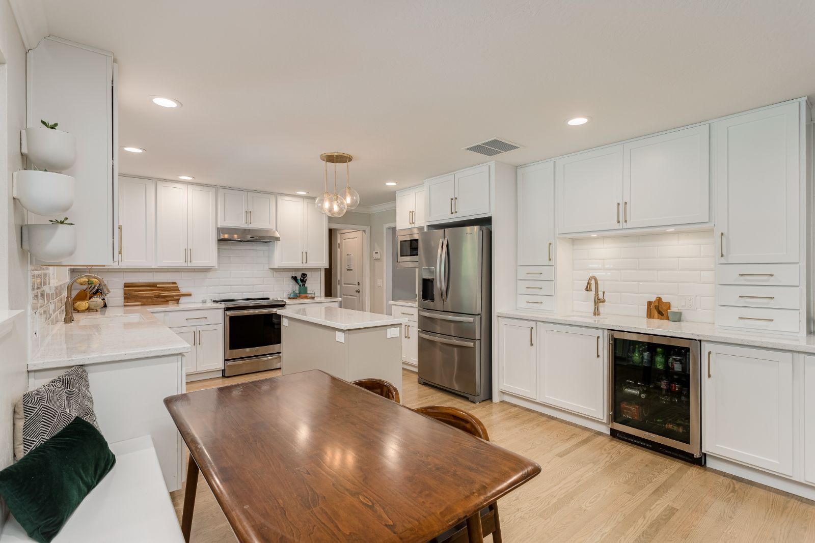 White shaker kitchen with quartz counters, brass hardware and a light oak floor