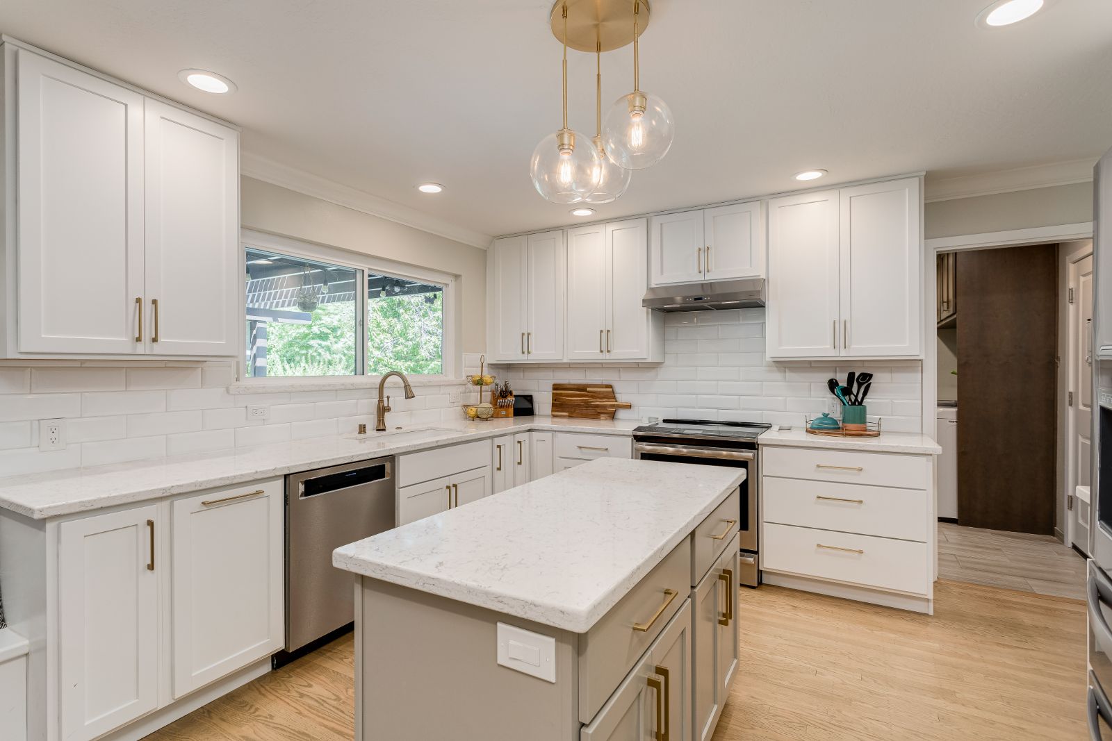 Remodeled kitchen with white shaker cabinets, quartz island and brass hardware