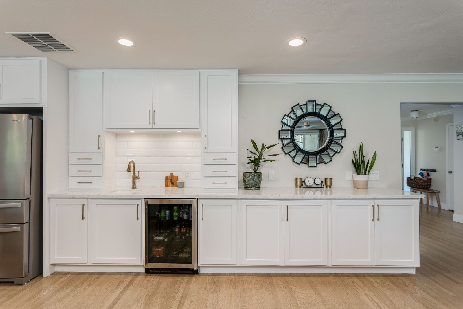 Built-in beverage bar with white cabinetry, quartz top and wine refrigerator